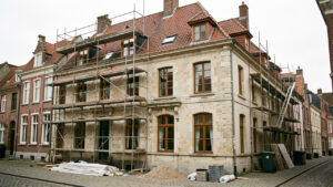 Maison ancienne belge située dans un quartier historique protégé, avec échafaudage et éléments de rénovation visibles.
