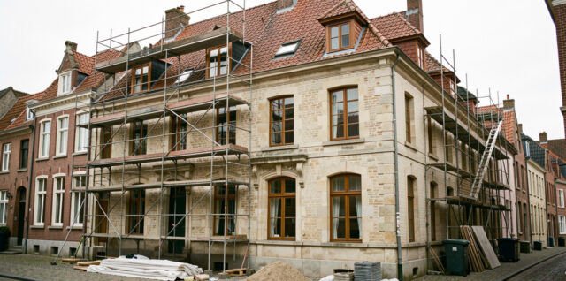 Maison ancienne belge située dans un quartier historique protégé, avec échafaudage et éléments de rénovation visibles.