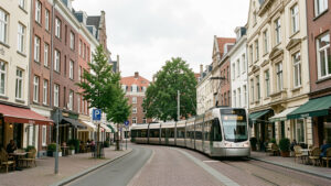 Vue urbaine réaliste de Bruxelles montrant des immeubles résidentiels, un tramway et un quartier mixte sous une lumière douce.